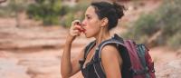 woman hiking with an inhaler wearing a backpack in a desert
